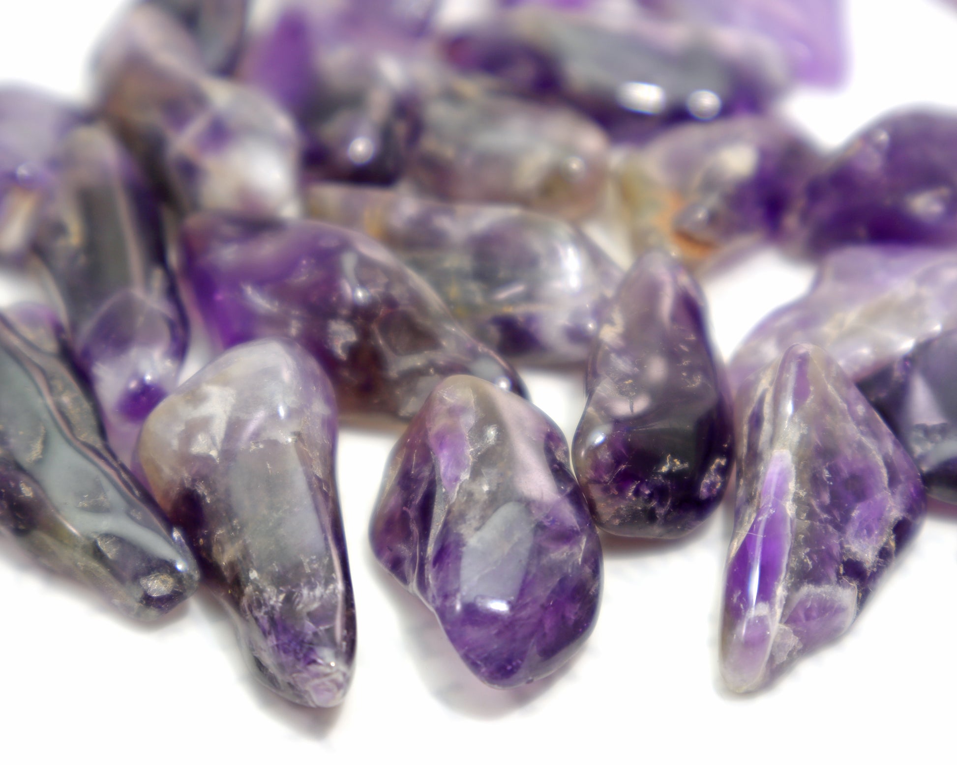 Close up of natural amethyst tumbled stones with smoky inclusions