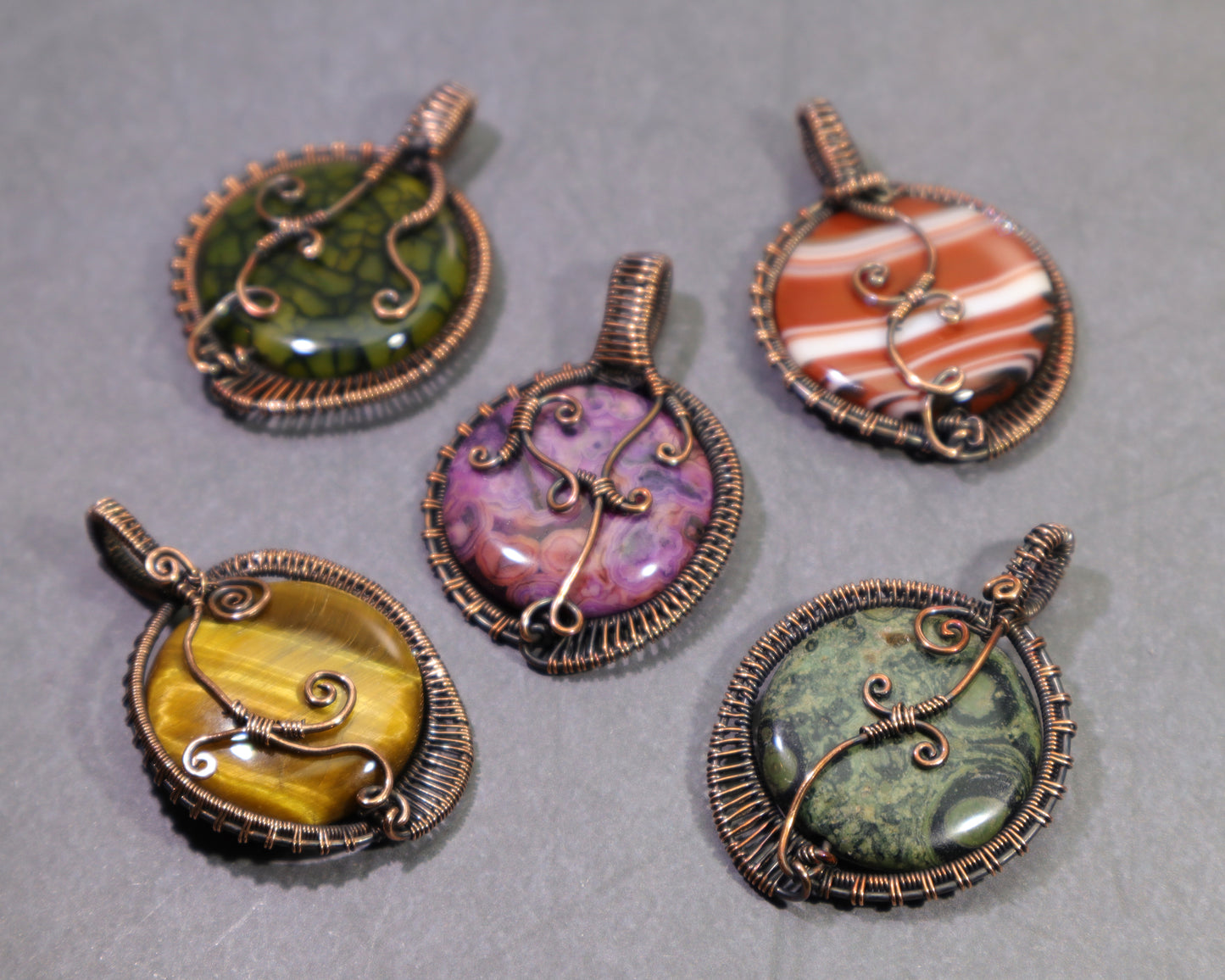 Nickel free hypoallergenic wire woven gemstone pendants in oxidized copper.  The stones shown are dragon vein agate, sardonyx, crazy lace agate, tiger eye and kambaba jasper.